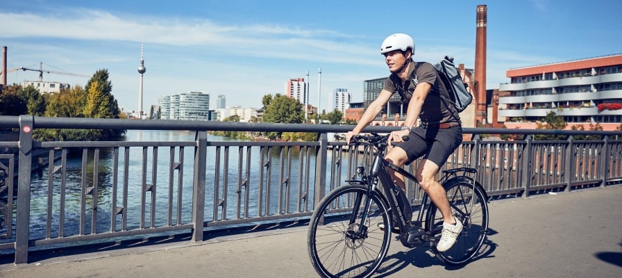Mann fährt auf seinem e-Bike über Brücke in Berlin